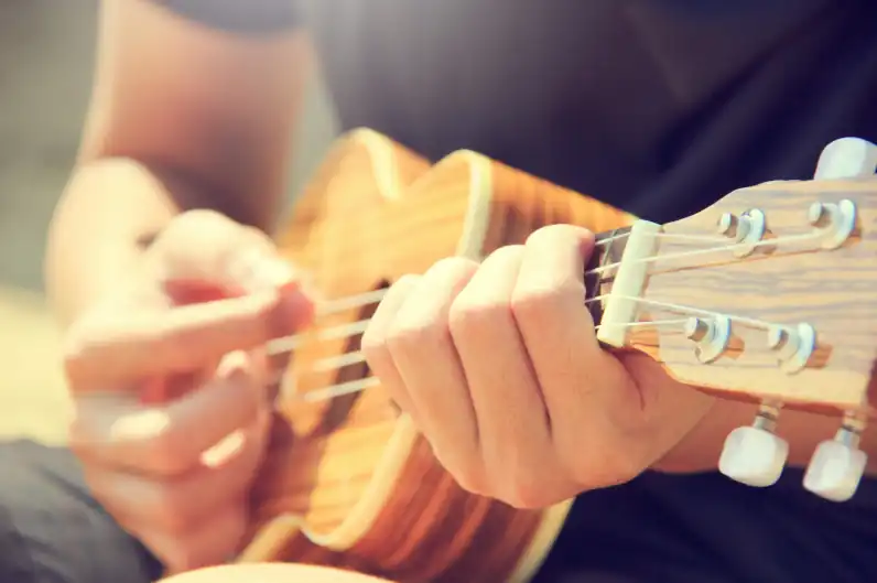 Ujęcie z bliska na ukulele, na którym ktoś gra piosenki.